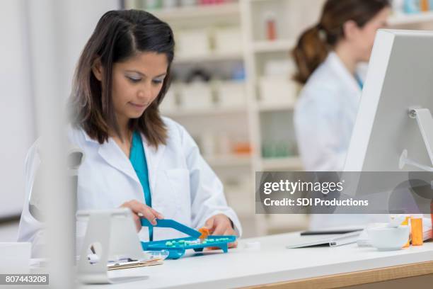 young pharmacist counts medication for fill a prescription - counting stock pictures, royalty-free photos & images
