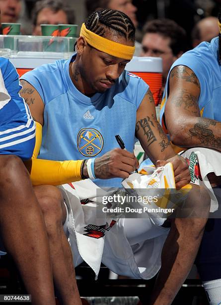 Allen Iverson of the Denver Nuggets autographs his shoes after leaving the game the Memphis Grizzlies and then giving them to fans at the Pepsi...