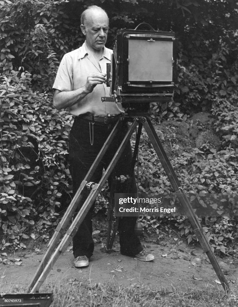 Strand Work American photographer Paul Strand adjusts the lens of his camera ...
