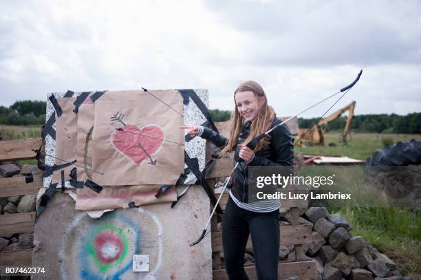 teenage girl standing next to her bow and arrow target with pride - 807453486,807453502,807453516,807462304,807462308,807462298,807462302,807462360,807462344,807462326,807462330,807462374,807480870,807484068,807484070,807484072,807486462,807486494,807486458,807486466 stockfoto's en -beelden