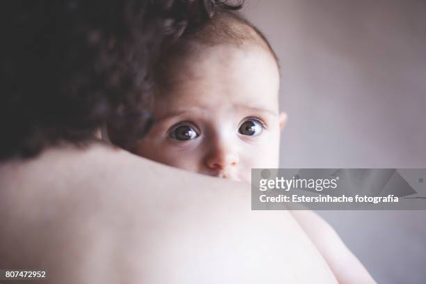 primer plano bebé mirando a cámara en brazos de su madre - primer plano stock pictures, royalty-free photos & images