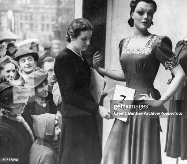 People, War and Conflict, pic: circa 1941, People look through the shop window at Selfridges, London, with a dress going on sale as clothes rationing...