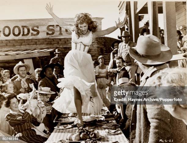 Cinema, American film actress Maureen O'Hara dances on the table in a still from the film "Man Of Truth", aka 'McLintock!', 1963