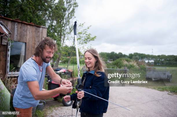 man teaching a teenage girl to shoot bow and arrow - 807453486,807453502,807453516,807462304,807462308,807462298,807462302,807462360,807462344,807462326,807462330,807462374,807480870,807484068,807484070,807484072,807486462,807486494,807486458,807486466 stockfoto's en -beelden