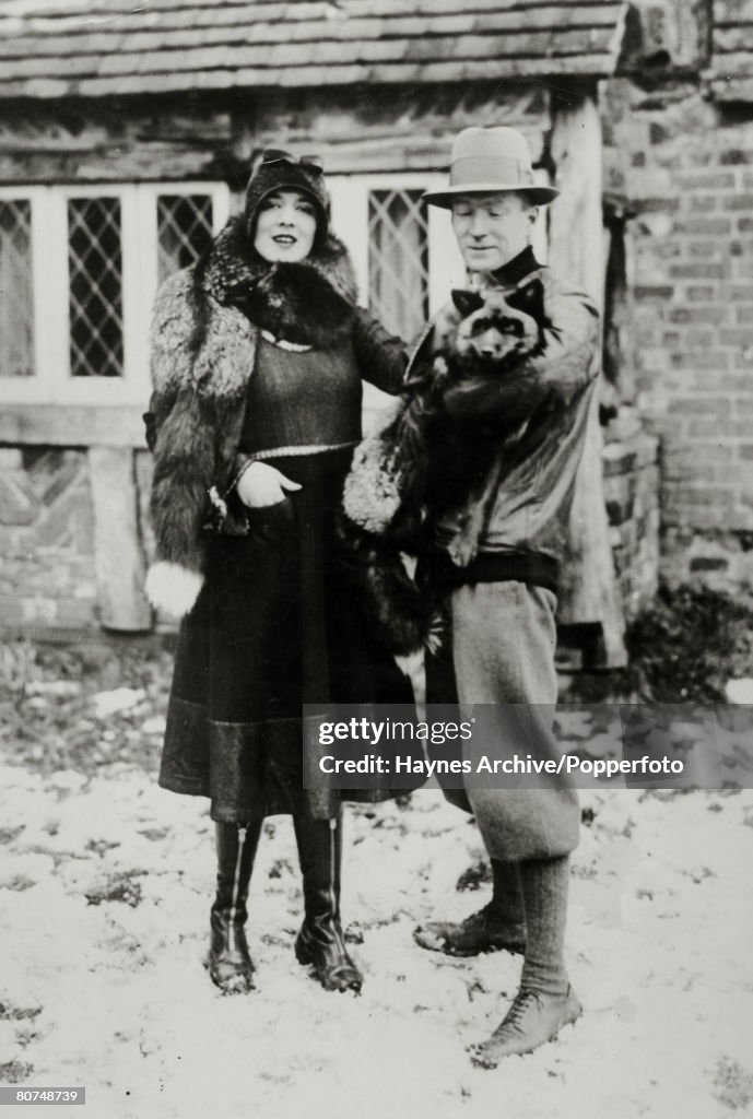Business Fur. pic: 1929. An attractive young woman wearing a fur poses in outdoor style clothes with a man holding a silver fox at a fur farm in Kent, England.