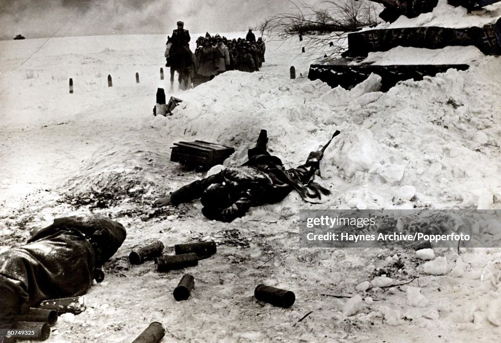 World War II 1942. A dead Russian soldier lies by a wrecked German tank as a troop of Russian soldiers pass during the battle of Stalingrad.