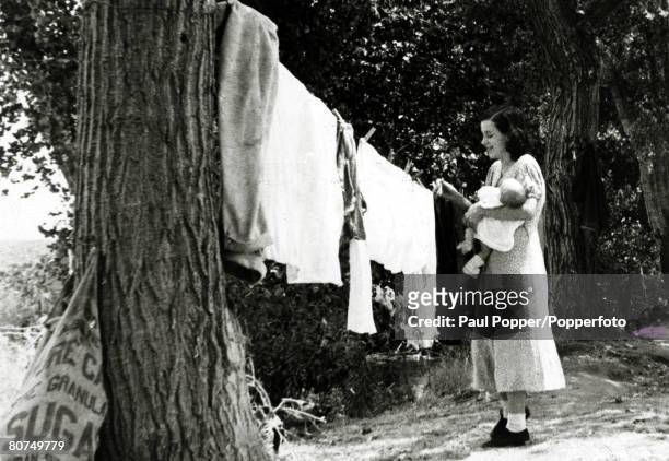 Depression Years, U,S,A, pic: circa 1930's, San Joaquin Valley, California, A young mother with her baby, hangs out the washing, one of many...