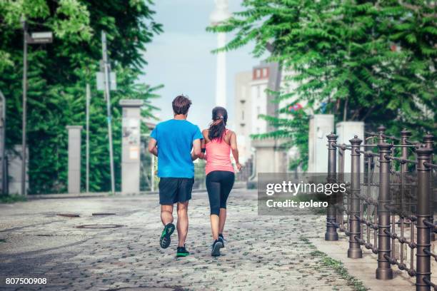 sportsman and sportswoman running in berlin city - funkmast stock pictures, royalty-free photos & images