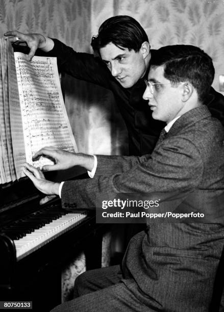 Music Personalities, pic: circa 1940's, John Barbirolli, celebrated English conductor pictured as he looks over a music score with the youthful...