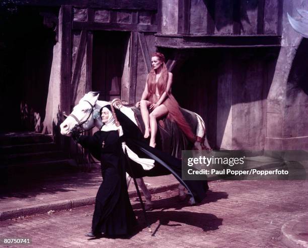 American film star Maureen O' Hara on top of a horse led by a nun during a scene in the film "Lady Godiva of Coventry"