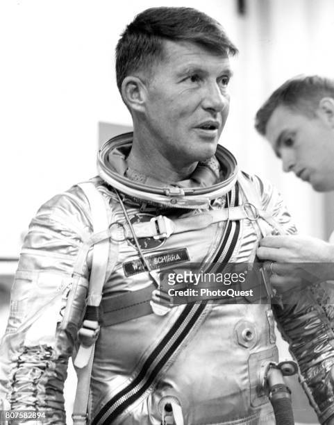 View of American astronaut Walter Schirra as his space suit is given final adjustments by technician Al Rochford in Hanger S, Cape Canaveral,...