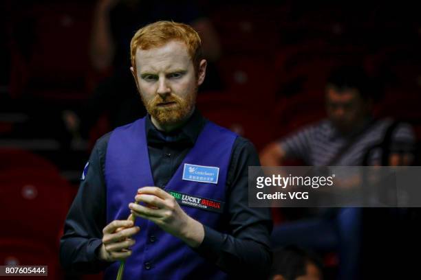 Anthony McGill of Scotland chalks the cue against Michael Georgiou of Cyprus and Antonis Poullos of Cyprus on day two of 2017 Snooker World Cup at...