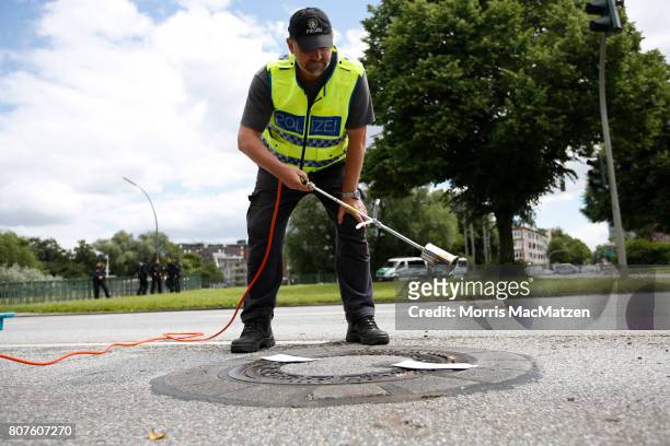 Police officer seals a manhole cover on a road near the Alster lake prior to the G20 Summit in Hamburg on July 4, 2017 in Hamburg, Germany. Hamburg...