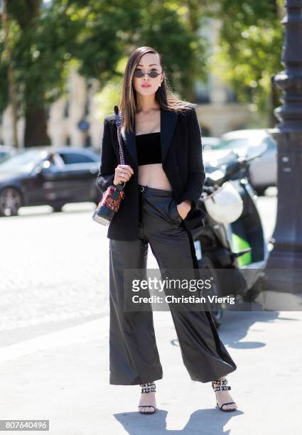 Chriselle Lim wearing cropped top, black wide leg leather pants, sandals outside Chanel during Paris Fashion Week - Haute Couture Fall/Winter...