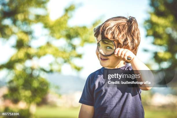 child looking through a magnifying glass - child magnifying glass imagens e fotografias de stock