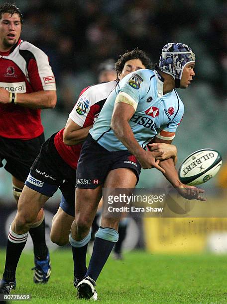 Kurtley Beale of the Waratahs passes the ball before being tackled by the Lions during the round 10 Super 14 match between the Waratahs and the Lions...