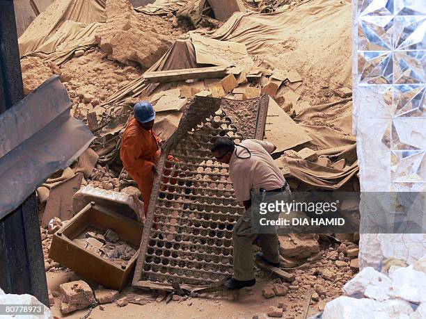 An Asian construction worker and an Iraqi contractor remove debris from the Ali al-Hadi shrine in the northern Iraqi city of Samarra on April 19,...