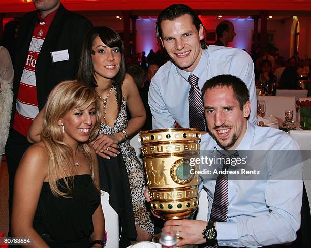 Franck Ribery and his wife Wahiba Ribery hold the trophy as Daniel van Buyten and his girlfriend Celine smile during the Bayern Munich champions...
