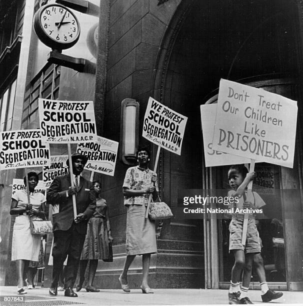 Demonstrators picket in front of a school board office protesting segregation of students.