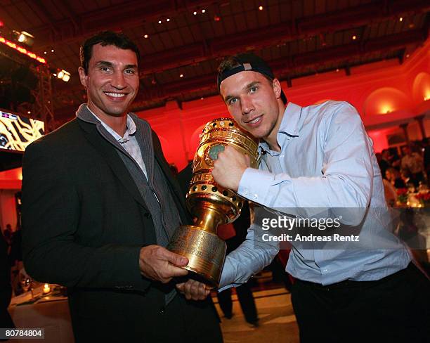 Lukas Podolski and boxer Vladimir Klitschko pose with the trophy during the Bayern Munich champions party after the DFB Cup Final match between...