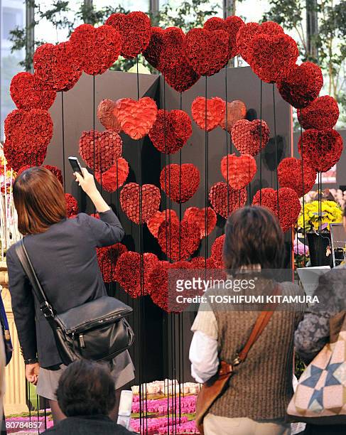 Visitors look at the flower artwork titled "Tsunagaru Kokoro" or "Connecting Heart" during the Flower Weeks 2008 event at the Marunouchi shopping...