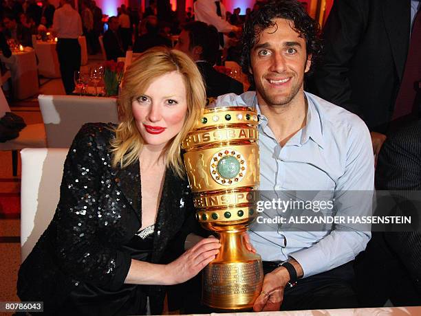 Bayern Munich's Italian striker Luca Toni poses with his girlfriend Italian model Marta Cecchetto and the German Cup trophy on early April 20, 2008...