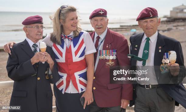 Tom Schaffer who was a paratrooper during the battle of the Ardennes poses for a photograph as younger paratroopers John Lynch and David Ramsay eat...