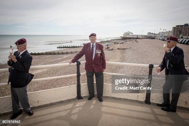 Tom Schaffer who was a paratrooper during the battle of the Ardennes poses for a photograph as younger paratroopers John Lynch and David Ramsay eat...