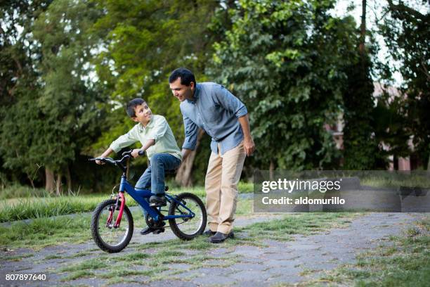 lateinischen vater sohn auf seinem fahrrad zu helfen - latin father and son stock-fotos und bilder