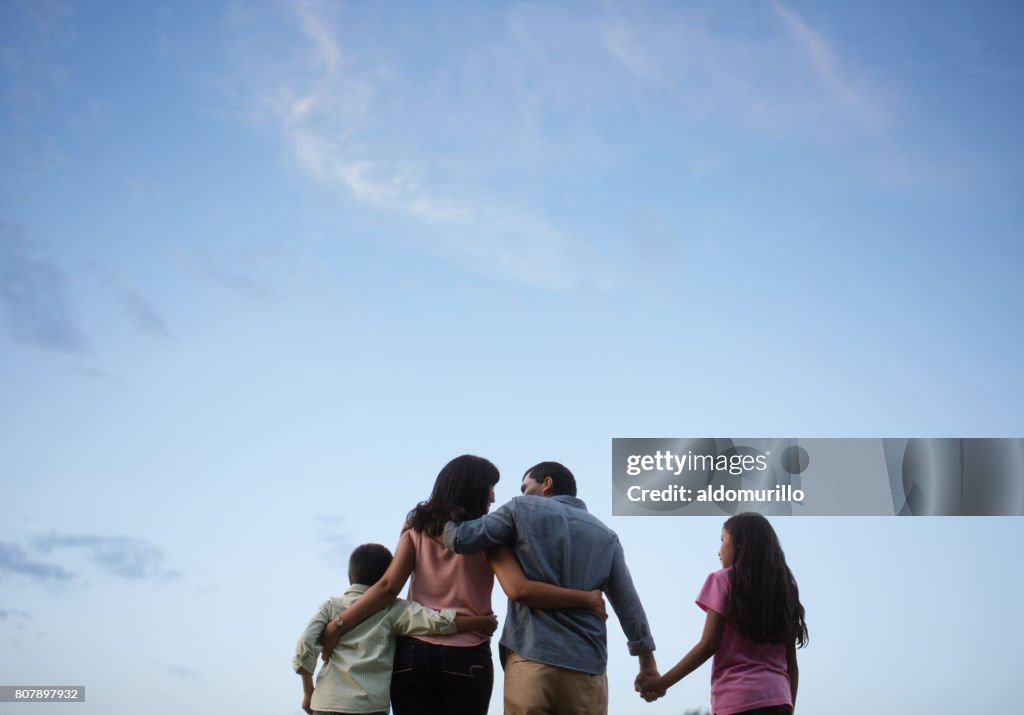 Latin family standing together with sky in background