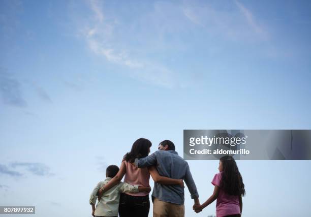latin family standing together with sky in background - back shot position stock pictures, royalty-free photos & images
