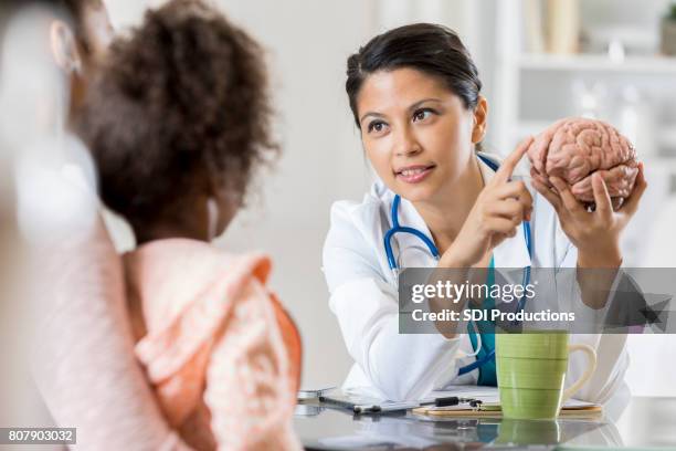 pediatric neurologist talks with young patient's mom - neurologist stock pictures, royalty-free photos & images