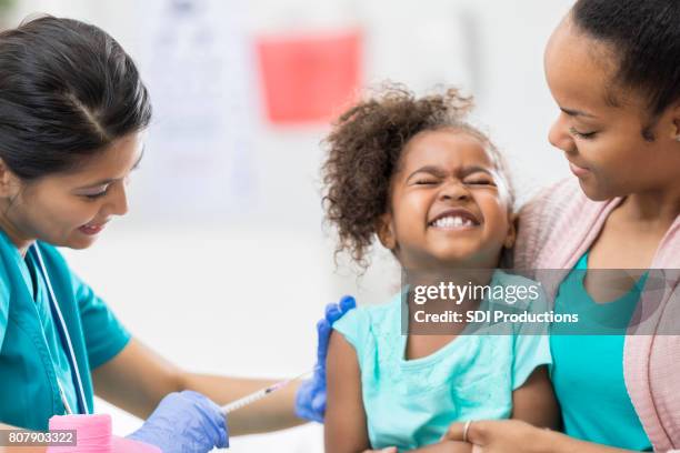 young girl grimaces while getting a shot - vaccine fear stock pictures, royalty-free photos & images