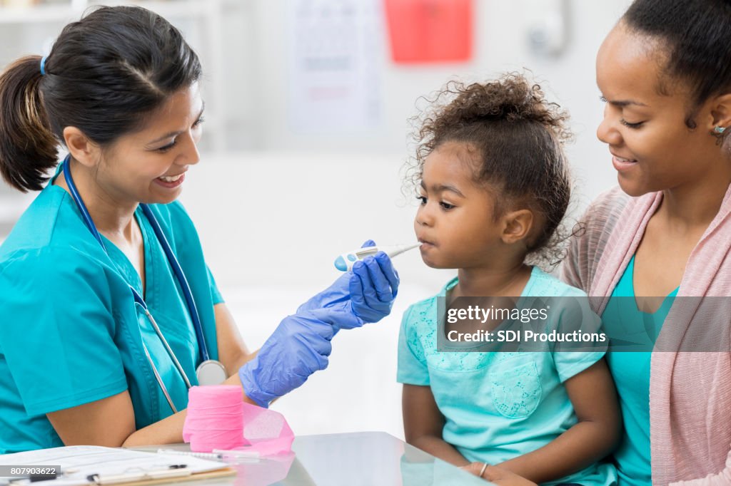 Nurse checks preschool age girl's temperature