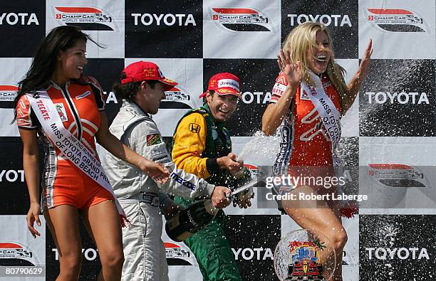 Will Power of Australia, driver of the KV Racing Technology DP01 Ford Cosworth, and Mario Dominguez of Mexico celebrate with champagne on the podium...