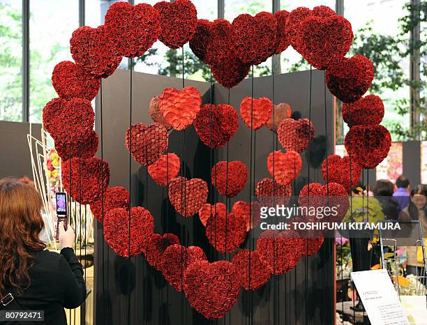 Woman takes a picture of the flower artwork titled "Tsunagaru Kokoro" or "Connecting Heart" during the Flower Weeks 2008 event at the Marunouchi...