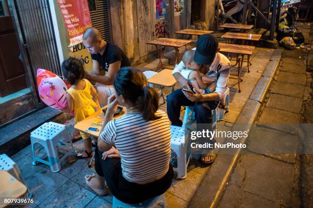 Vietnamese family is watching their smartphone on a street in Hanoi, Vietnam, on 5 June 2017. Hanoi, is the capital of the Democratic Republic of...