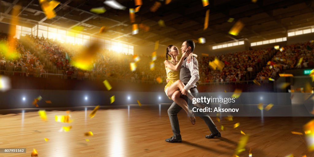 Couple dancers ardently perform the latin american dance on a large professional stage with sparkle fireworks