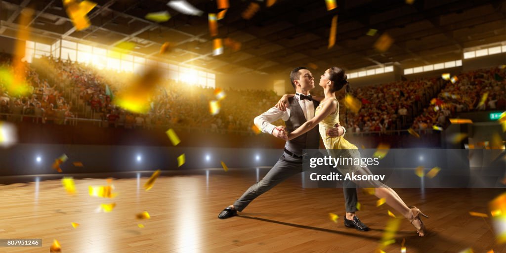 Couple dancers ardently perform the latin american dance on a large professional stage with sparkle fireworks