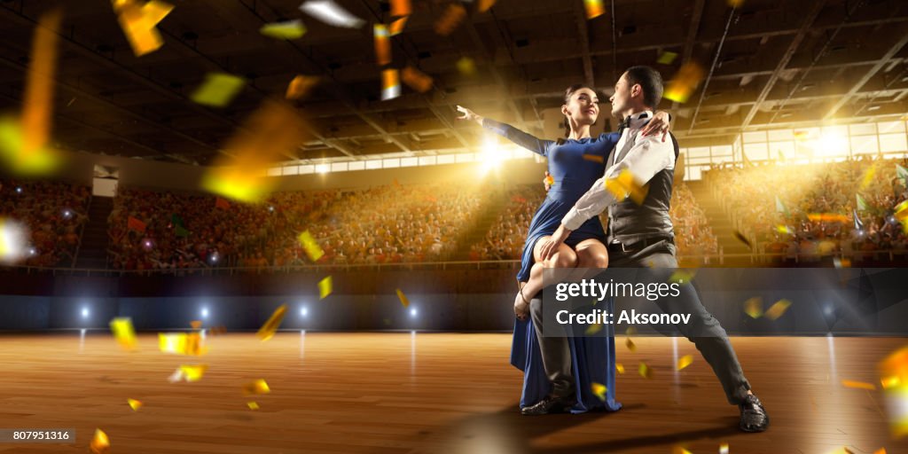 Couple dancers ardently perform the latin american dance on a large professional stage with sparkle fireworks