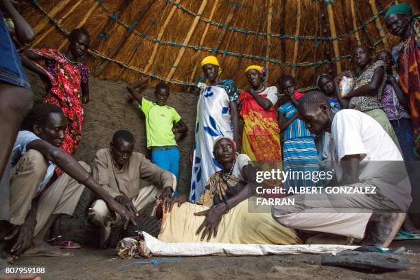 Relatives assist Nyanom Gay , a 26-year-old mother of four, after being infected with malaria in Padding, near Lankien, Jonglei, South Sudan, on July...
