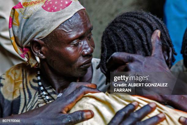 Nyakong Kiir reacts as she assists her daughter-in-law Nyanom Gay , a 26-year-old mother of four, after being infected with malaria in Padding, near...