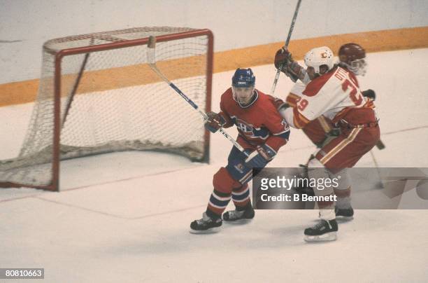 Canadian ice hockey player Guy Carbonneau of the Montreal Canadiens and American Joel Otto of the Calgary Flames skate in front of the Flames' net...
