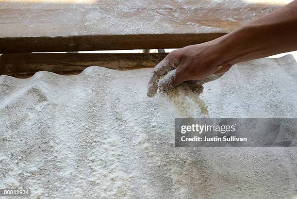 Boudin Bakery bread baker Calixta Luna sprinkles flour onto a pan as he rolls dough for sourdough bread at Boudin Bakery April 21, 2008 in San...
