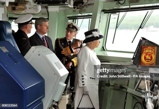 Britain's Queen Elizabeth II, the Duke of Edinburgh and Canadian Prime Minister Stephen Harper , stand on the bridge of HMCS St John's, before a...