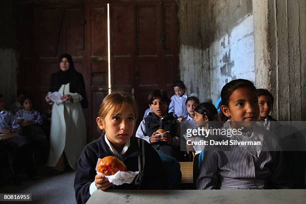 Palestinian schoolgirls continue with their lessons eating vitamin-enriched snacks provided daily by the World Food Program April 21, 2008 in the...