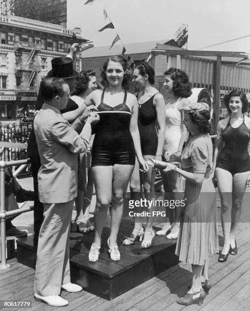Pin-up artist Earl Moran measures the bust of entrant Jean Desmond during a beauty contest, circa 1935.