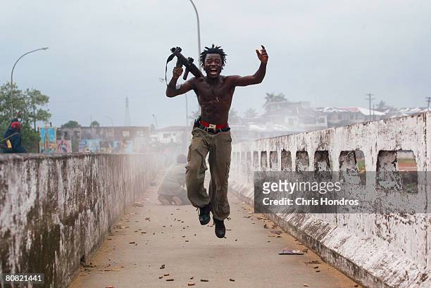 Joseph Duo, a Liberian militia commander loyal to the government, exults after firing a rocket-propelled grenade at rebel forces at a key strategic...