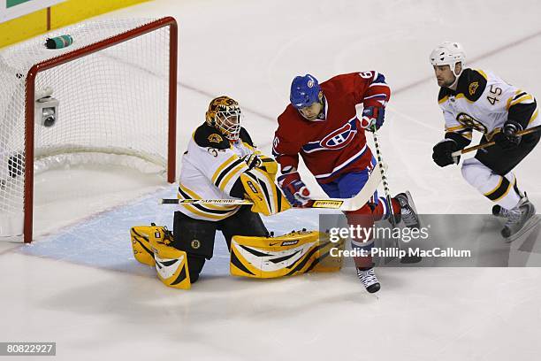 Goaltender Tim Thomas of the Boston Bruins attempts to slow down Tom Kostopoulos of the Montreal Canadiens as Mark Stuart helps defend during game...