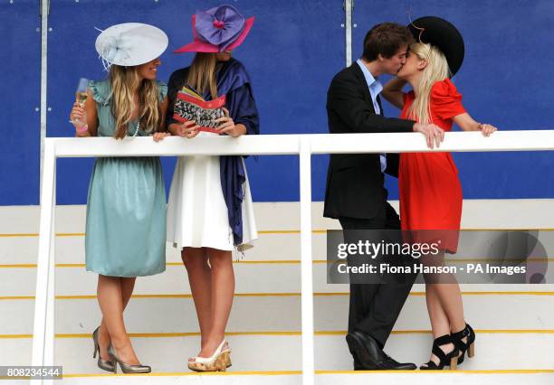 Harry Irby and Lucy Hemelryk embrace as Cat O'Donnell and Debra Glucksman watch during Ladies Day at Newbury Races.